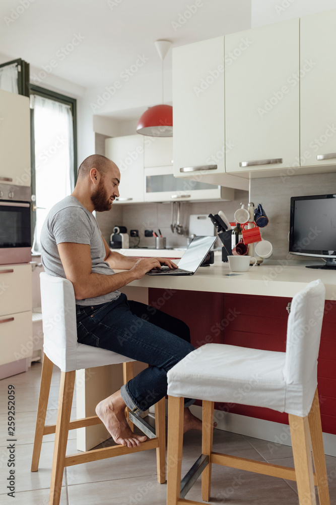 Adult Couple Using a Laptop From a Kitchen during the Morning Breakfast Adult Couple Using a Laptop From a Kitchen during the Morning Breakfast