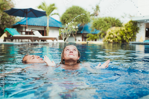 Young couple playing in a pool photo