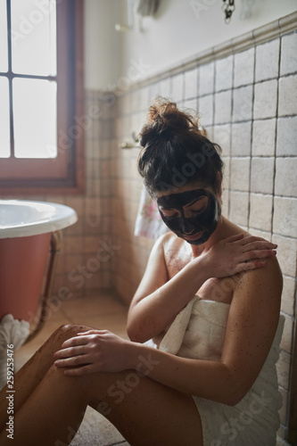 Woman with face mask applying body scrab. photo