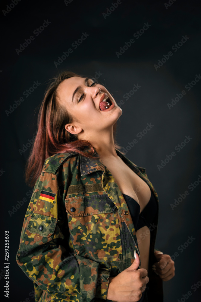 beautiful young girl with red hair and in army jacket on black background. beautiful young girl with red hair and in army jacket on black background.