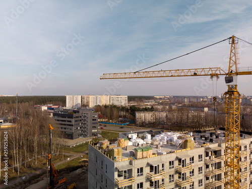 Aerial of a building site with a large operating bright yellow crane near a house