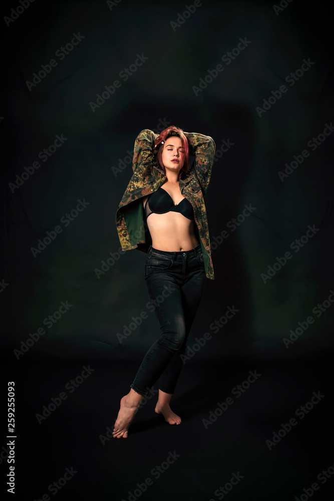 beautiful young girl with red hair and in army jacket on black background. beautiful young girl with red hair and in army jacket on black background.