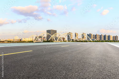 Asphalt road and city skyline panorama with bridge construction in shanghai at sunset