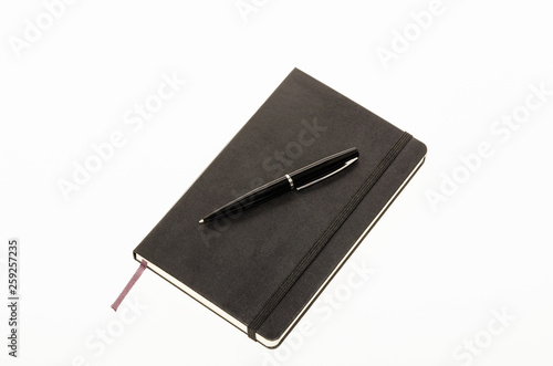 Black leather notebook with pen isolated on a white background. Moleskin 