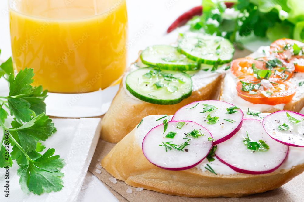 Healthy breakfast: sandwiches with cream cheese and vegetables, and orange juice on a light background. Healthy breakfast: sandwiches with cream cheese and vegetables, and orange juice on a light background.