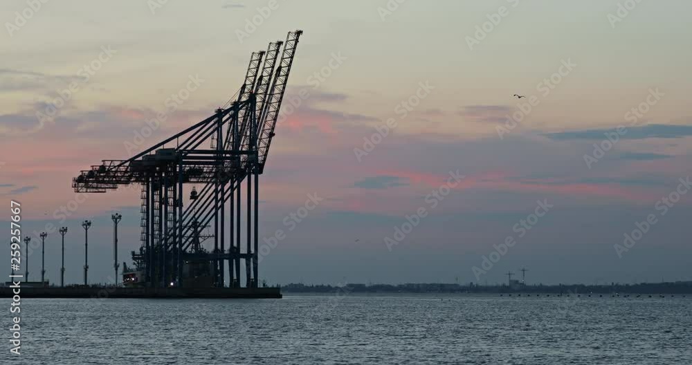 Huge industrial cranes in the sea port at beautiful sunset on summer evening. Cityscape and seaside. Huge industrial cranes in the sea port at beautiful sunset on summer evening. Cityscape and seaside.