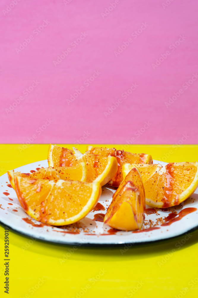 Orange slices with chilli powder and chamoy on colorful background