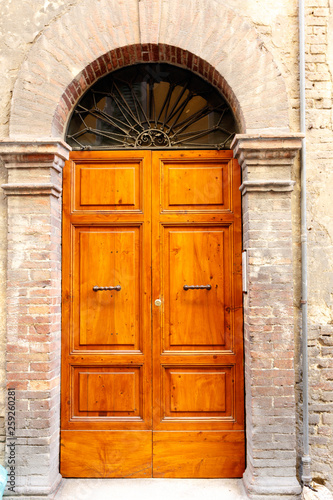 Brown wooden double doors in an arched stone doorway