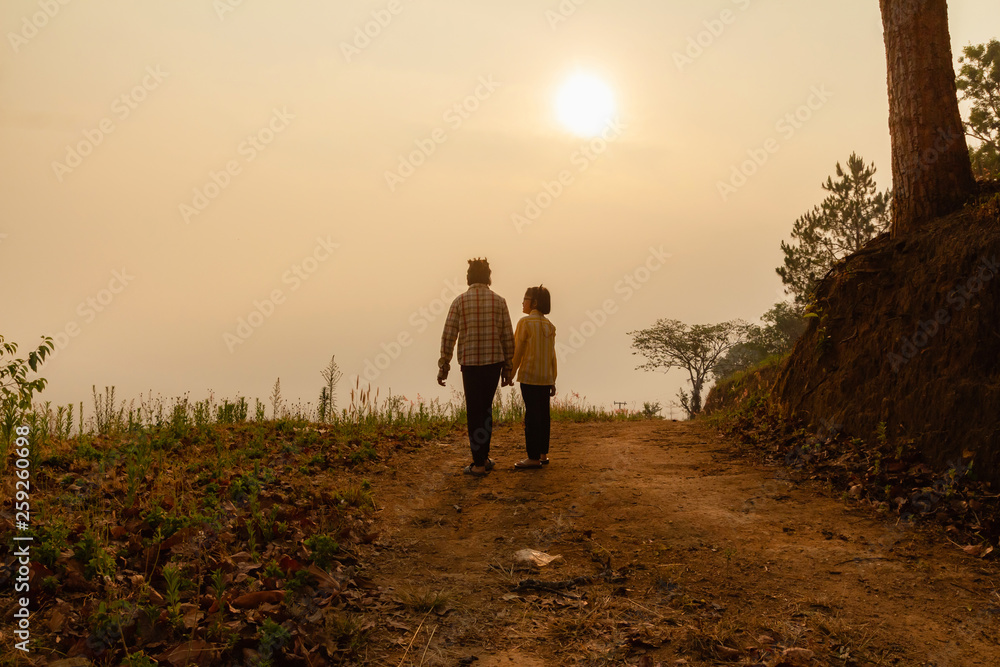 Two children walking on mountain trail at sunset