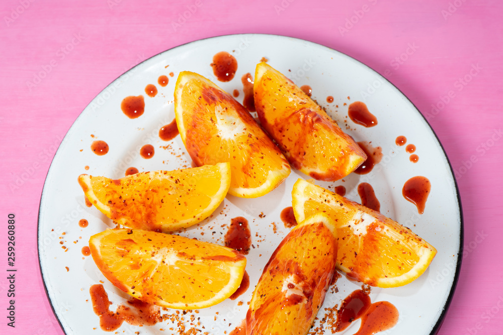 Orange slices with chilli powder and chamoy on colorful background Orange slices with chilli powder and chamoy on colorful background