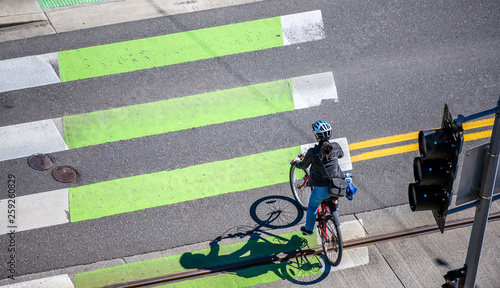 Woman on bicycle crosses the road at pedestrian crossing