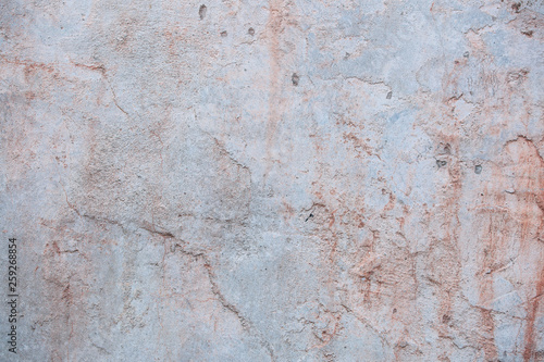 Red concrete wall with scratches, cracks, dust, crevices, roughness. Can be used as a poster or background for design.