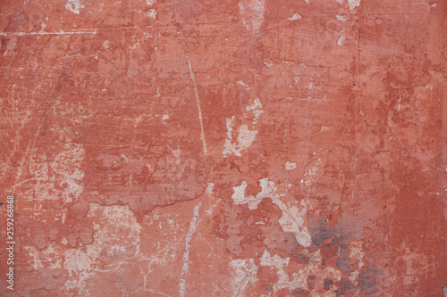 Red concrete wall with scratches, cracks, dust, crevices, roughness. Can be used as a poster or background for design.