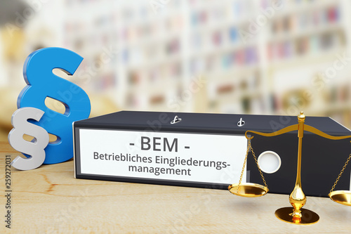 Betriebliches Eingliederungsmanagement (BEM) – Gesetz/Recht. Ordner auf Schreibtisch mit Beschriftung neben Paragraf und Waage. Anwalt photo