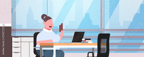 fat obese woman manager using laptop eating chocolate fatty overweight girl worker sitting workplace modern office interior unhealthy lifestyle concept portrait horizontal