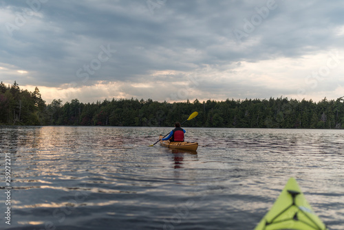 a woman mid paddle kayaking in the middle of the lake