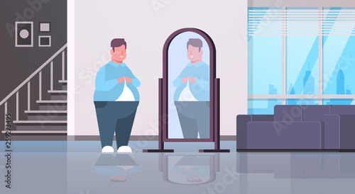 sad overweight man looking at himself reflection in mirror over size guy buttoning shirt unhealthy lifestyle obesity concept modern apartment interior flat full length horizontal