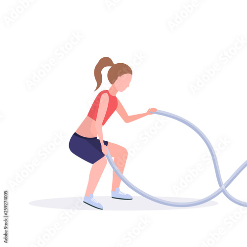 sporty woman doing crossfit exercises with battle rope girl training in gym cardio workout healthy lifestyle concept flat white background full length