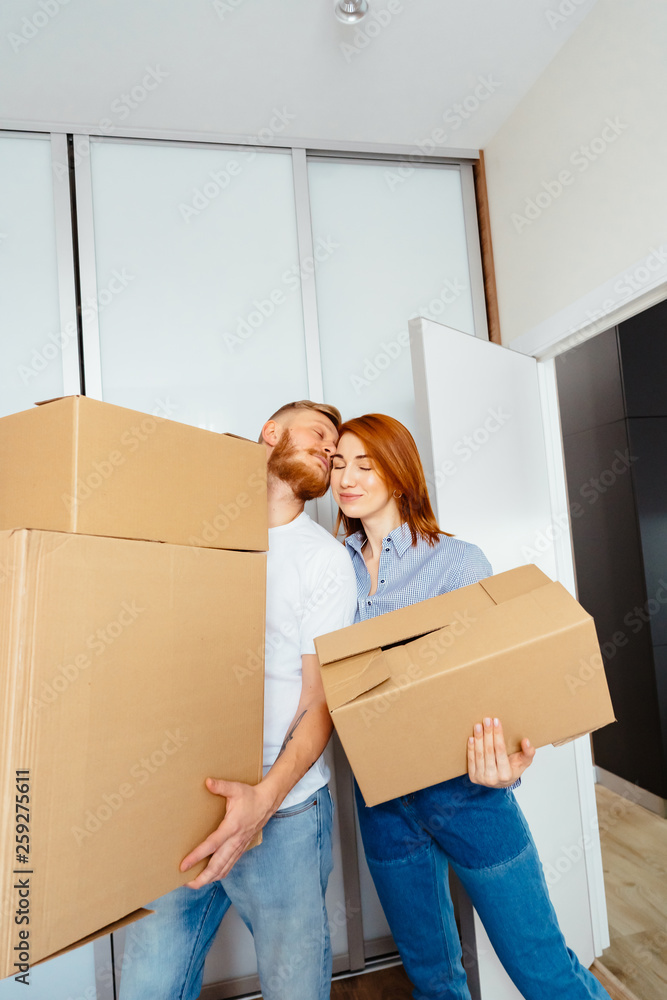 Happy couple holding cardboard boxes and moving to new place