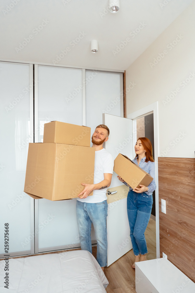 Happy couple holding cardboard boxes and moving to new place Happy couple holding cardboard boxes and moving to new place