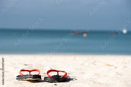 The sandals places on white-yellow sand beach on the island at the sea of Thailand on some holiday weekend.