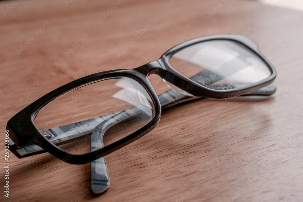 Black-framed glasses on a wooden stool