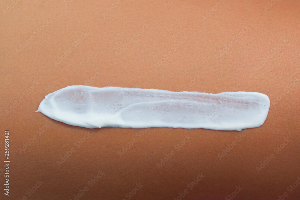 Fototapeta premium Woman applying sun cream lotion on legs. Skin care. A Female with sunscreen on beautiful legs on beach. Sun protection