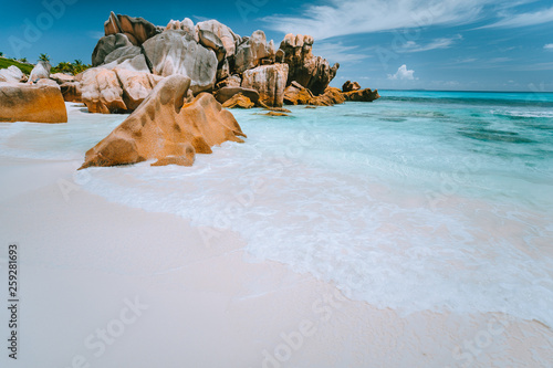 Granite rocks boulders on Anse Cocos beach, Seychelles. Pure white sand, turquoise water, blue sky. Vacation travel concept