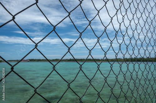 A Close up of fence with blurry turquoise water on the background taken at Harapan Island, Indonesia