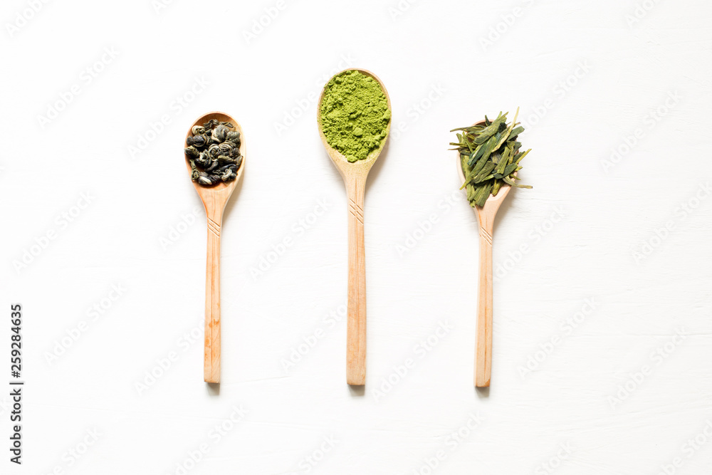 Biluochun, Matcha and Longjing. Chinese leaf and Japanese powdered green tea in a spoon on a white background. Top view and central location. Biluochun, Matcha and Longjing. Chinese leaf and Japanese powdered green tea in a spoon on a white background. Top view and central location.