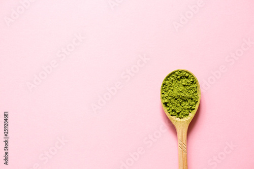 Matcha. Japanese powdered green tea in a spoon on a pink background. Top view and copy space.