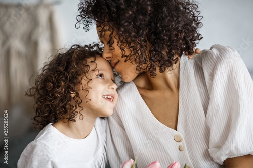 Happy mother's day, daughter gives a bouquet of tulips. African-American girl with a smile without teeth.
