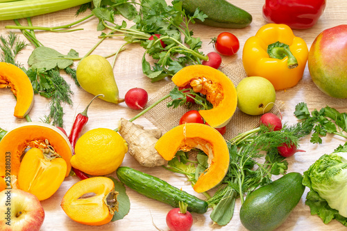 vegetables fruits and greens on wooden background. pear  hot red pepper  pumpkin  persimmon  mango  cucumber  radish  lemon  Apple  dill  parsley  cabbage