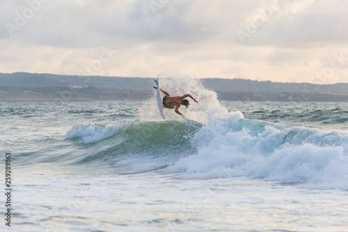 Surfer with a tanned body performs a trick on a short board - a jump over the waves.  photo