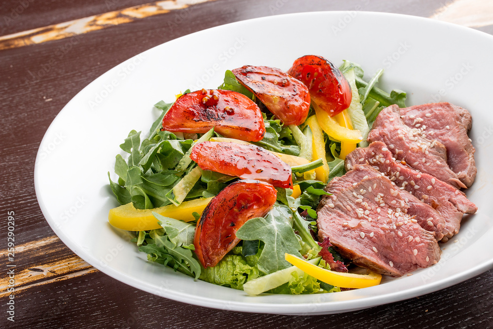 Salad with roast beef and sun-dried tomatoes on dark background Salad with roast beef and sun-dried tomatoes on dark background