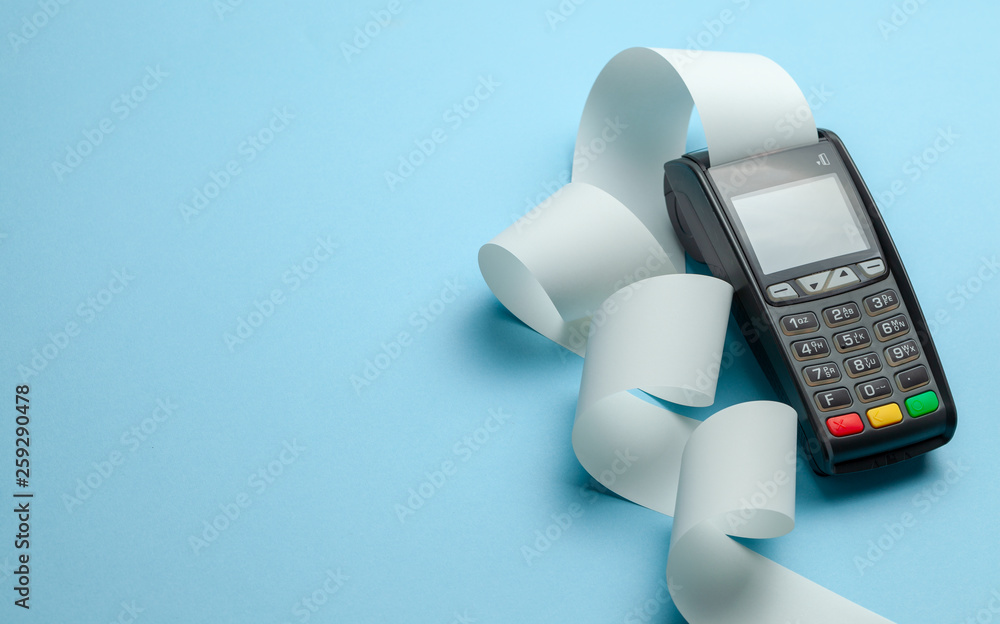 Foto Stock Terminal cash register machine POS for payments and long roll  cash tape on blue background. Copy space for text. | Adobe Stock