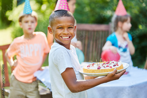 Boy holding cake at birthday party