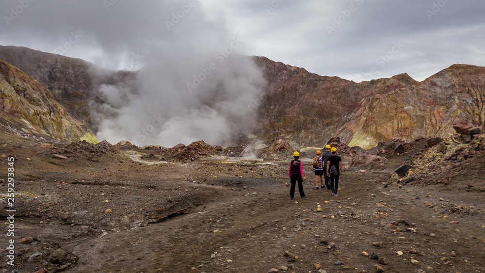 Wide angle landscape view of tourists hiking towards the active vents in the crater of White Island Volcano, New Zealand.