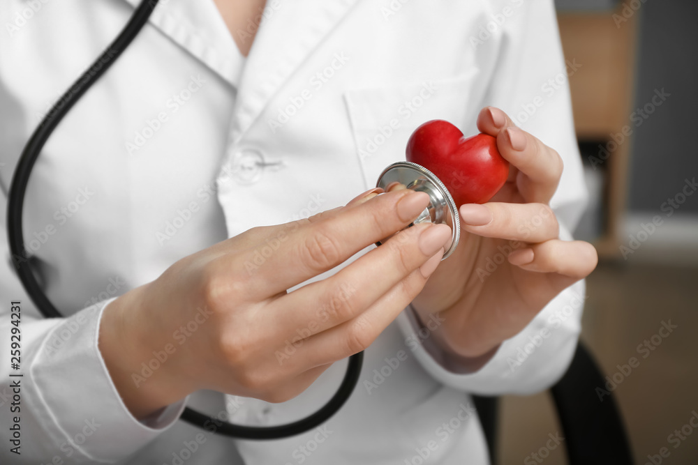 Cardiologist with red heart and stethoscope in clinic, closeup Cardiologist with red heart and stethoscope in clinic, closeup
