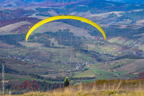 Paraglider flying over Carpathian mountains in summer autumn day. Borzhava. Ukraine.