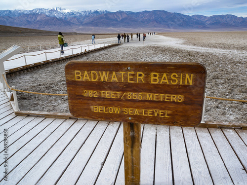 Death Valley, California, A sign for the Badwater Basin and pedestrians on path.