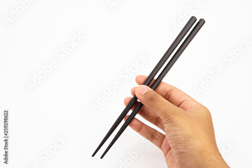 A hand holding a black wooden chopsticks isolated on white background 