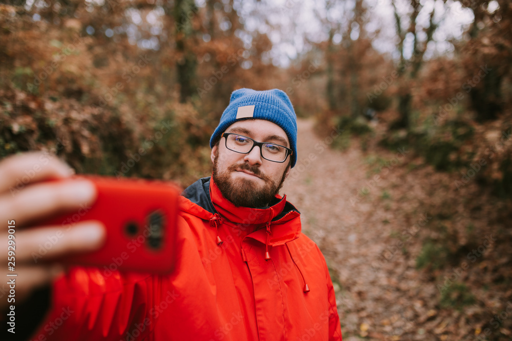 Young man takes a picture in the middle of the woods with his mobile phone Young man takes a picture in the middle of the woods with his mobile phone