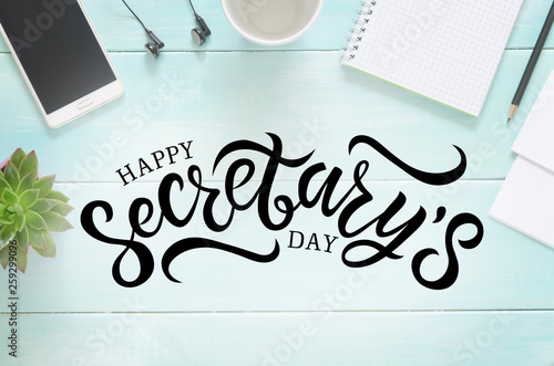 Desk with pencil, paper, cup, phone, headphones, notebook and succulent. Hand written lettering Happy Secretary's day