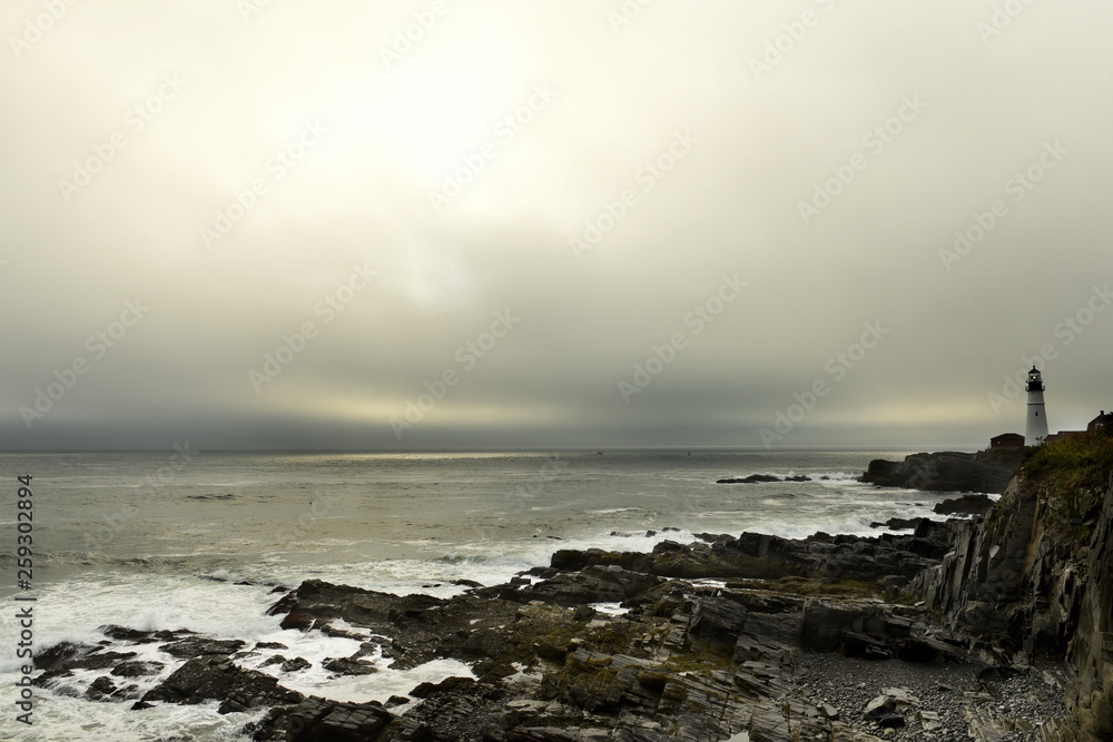 Obraz premium Lighthouse on the wild rocky shores of the Atlantic Ocean. USA. Maine. Portland. The oldest lighthouse of America.