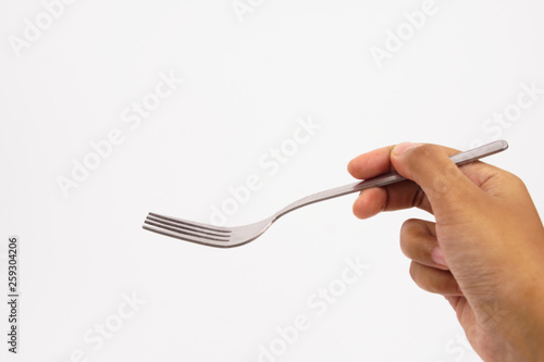 A hand holds steel silver fork isolated on white background  © Akmalism