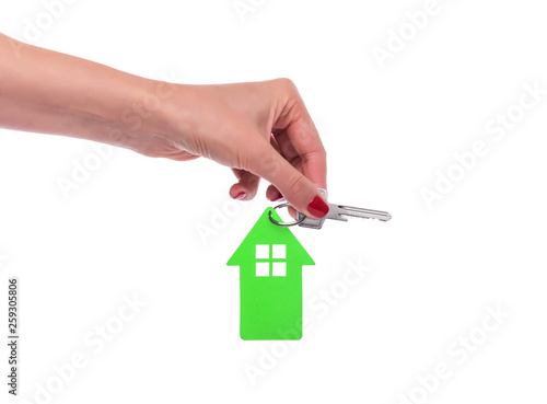 Beautiful female hand holds a key with a keychain in the form of a house. On a white.