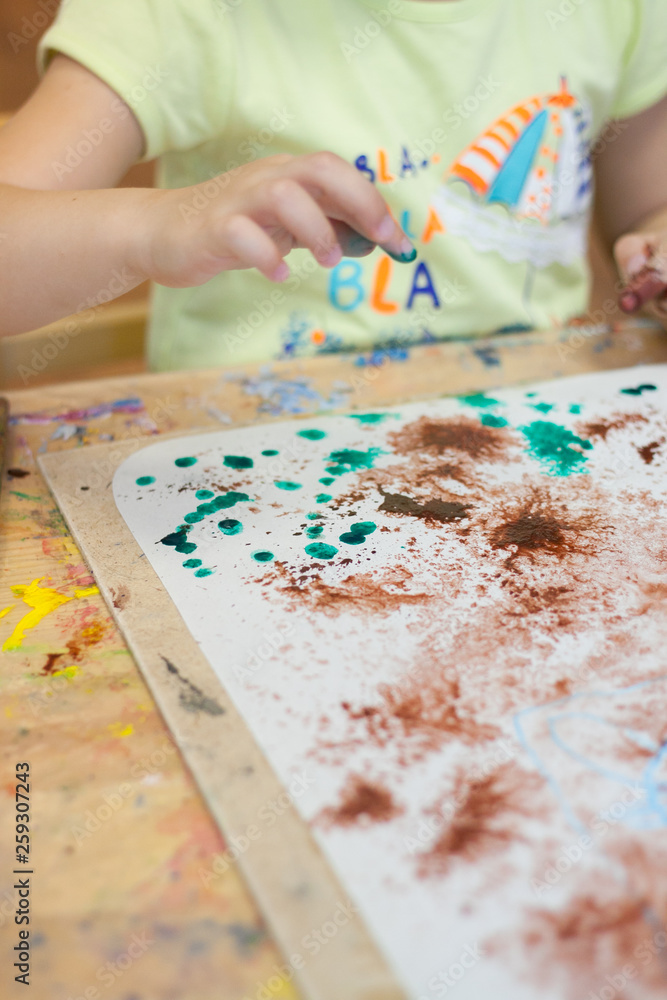 Bright paints, paper, brushes in the children's drawing lesson. Children's drawings, hands Bright paints, paper, brushes in the children's drawing lesson. Children's drawings, hands