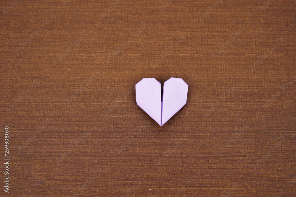 An origami paper heart isolated on wooden texture background An origami paper heart isolated on wooden texture background