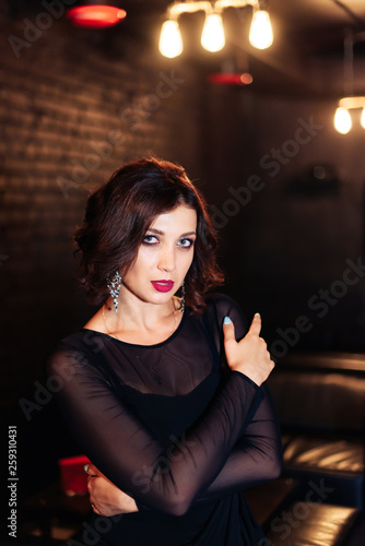 portrait of a beautiful brunette girl in a black dress in a dark room 1